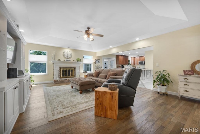 7 Mcclay Village Cir, Saint Peters, MO 63376 - living area with a tray ceiling, a ceiling fan, dark wood-type flooring, a fireplace, and recessed lighting