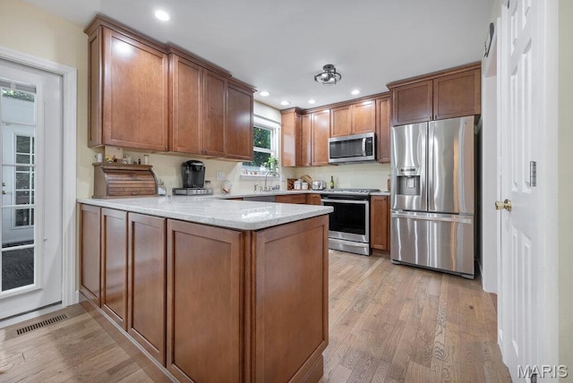 7 Mcclay Village Cir, Saint Peters, MO 63376 - kitchen with stainless steel appliances, a peninsula, light wood-type flooring, recessed lighting, and brown cabinetry