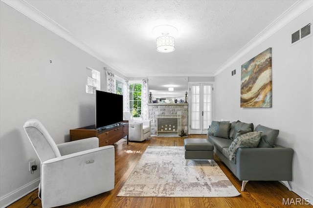 7248 Dorset Ave, University City, MO 63130 - living room with crown molding, wood finished floors, a textured ceiling, and a stone fireplace