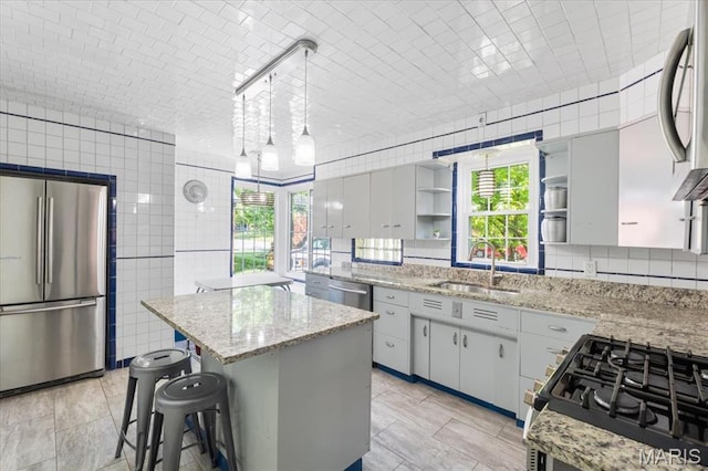 7248 Dorset Ave, University City, MO 63130 - kitchen featuring appliances with stainless steel finishes, a center island, open shelves, light stone counters, and a kitchen bar