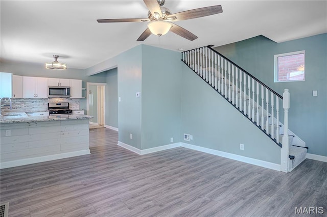 6557 Marmaduke Ave, Saint Louis, MO 63139 - unfurnished living room featuring stairs, wood finished floors, and a ceiling fan