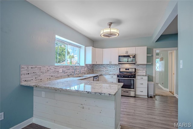 6557 Marmaduke Ave, Saint Louis, MO 63139 - kitchen featuring appliances with stainless steel finishes, light stone countertops, white cabinets, and decorative backsplash