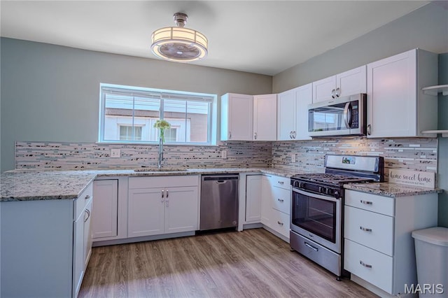 6557 Marmaduke Ave, Saint Louis, MO 63139 - kitchen featuring appliances with stainless steel finishes, white cabinets, tasteful backsplash, and light stone counters