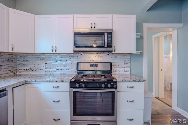6557 Marmaduke Ave, Saint Louis, MO 63139 - kitchen featuring appliances with stainless steel finishes, white cabinets, light stone countertops, and wood finished floors