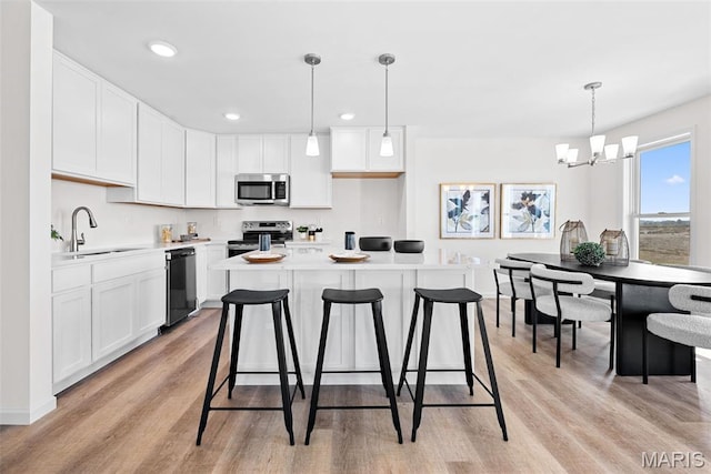 2921 Memphis St, Saint Charles, MO 63301 - kitchen with stainless steel appliances, light wood-style floors, white cabinetry, a kitchen breakfast bar, and recessed lighting