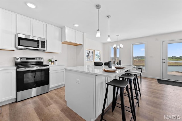 2921 Memphis St, Saint Charles, MO 63301 - kitchen featuring appliances with stainless steel finishes, light wood-type flooring, white cabinets, a chandelier, and recessed lighting