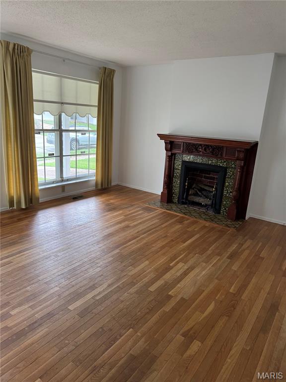 11646 Esperanza Dr, Florissant, MO 63033 - unfurnished living room featuring a textured ceiling, hardwood / wood-style flooring, and a high end fireplace