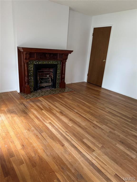 11646 Esperanza Dr, Florissant, MO 63033 - unfurnished living room featuring a tiled fireplace and wood-type flooring