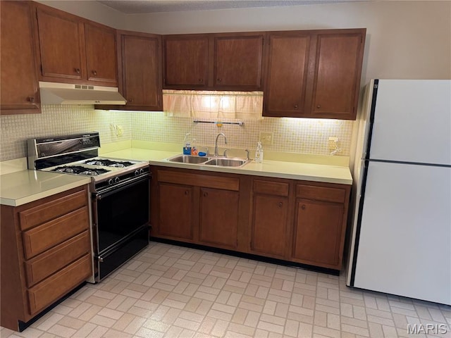11646 Esperanza Dr, Florissant, MO 63033 - kitchen with freestanding refrigerator, gas range, under cabinet range hood, light countertops, and decorative backsplash