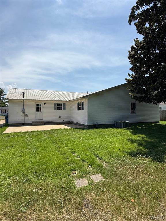 804 W Bain St, Dexter, MO 63841 - rear view of house with a patio area, a lawn, and a metal roof