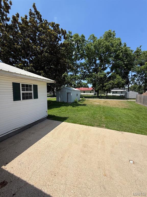 804 W Bain St, Dexter, MO 63841 - view of grassy yard featuring a patio area and a storage unit