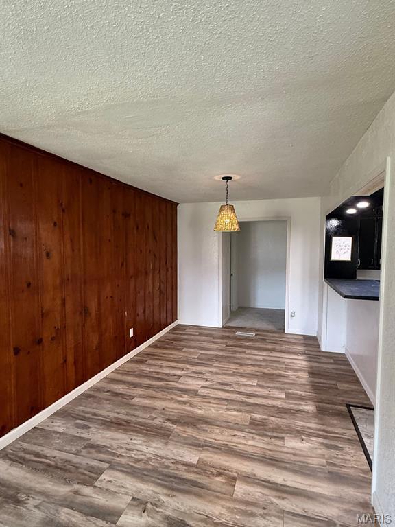 804 W Bain St, Dexter, MO 63841 - unfurnished dining area with wood finished floors, a textured ceiling, and wood walls