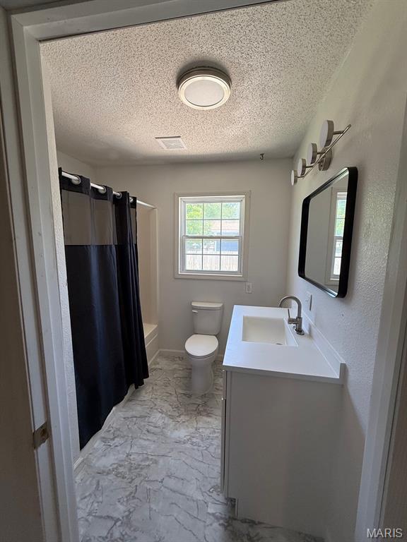 804 W Bain St, Dexter, MO 63841 - full bath featuring vanity, a textured ceiling, and marble look tiles