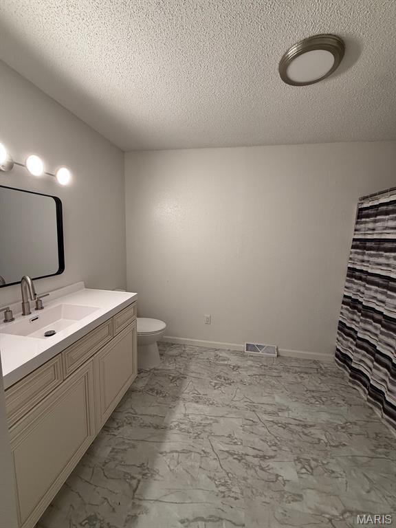 804 W Bain St, Dexter, MO 63841 - bathroom with marble finish floors, vanity, a textured ceiling, and a shower with shower curtain