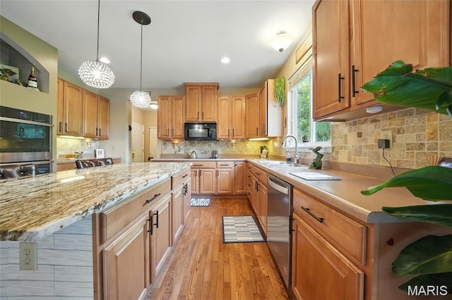 27 Carlton Lake Ct, Wentzville, MO 63385 - kitchen with stainless steel appliances, tasteful backsplash, light wood-style floors, hanging light fixtures, and a center island