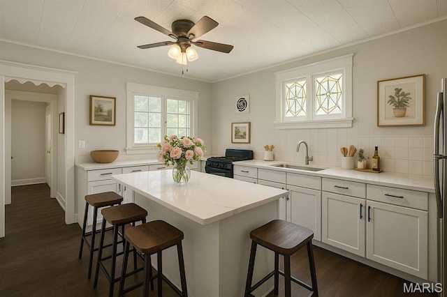 4707 Primm St, Saint Louis, MO 63116 - kitchen with a breakfast bar area, ornamental molding, dark wood-style flooring, light countertops, and a center island
