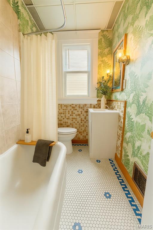4707 Primm St, Saint Louis, MO 63116 - bathroom featuring wallpapered walls, vanity, shower / bath combination with curtain, tile patterned floors, and tile walls