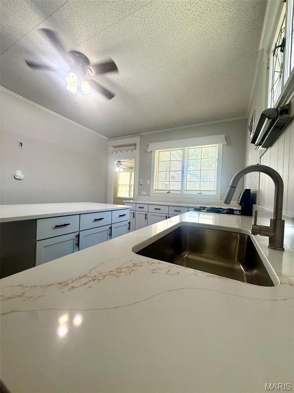 4707 Primm St, Saint Louis, MO 63116 - kitchen with ornamental molding, light stone counters, ceiling fan, and gray cabinets