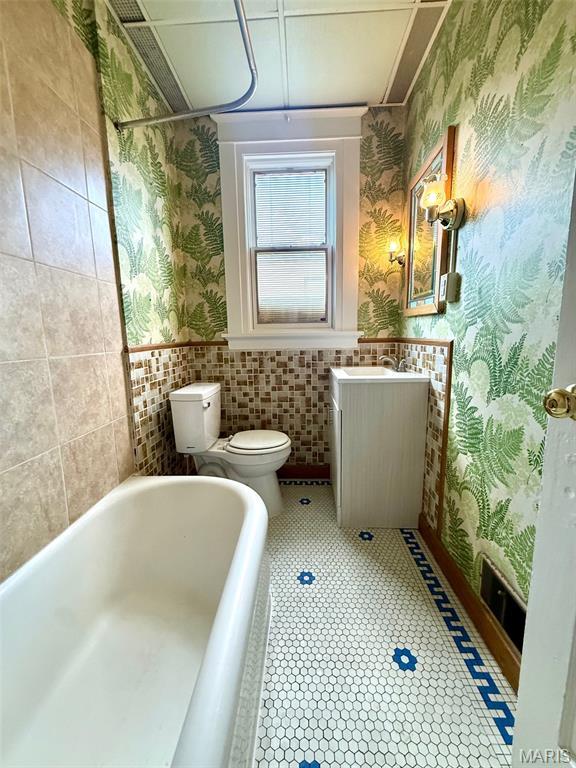 4707 Primm St, Saint Louis, MO 63116 - bathroom featuring wallpapered walls, a tub, vanity, and wainscoting