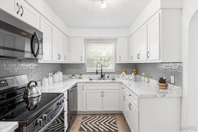 407 N 28th St, Belleville, IL 62226 - kitchen with appliances with stainless steel finishes, white cabinets, light wood finished floors, and tasteful backsplash
