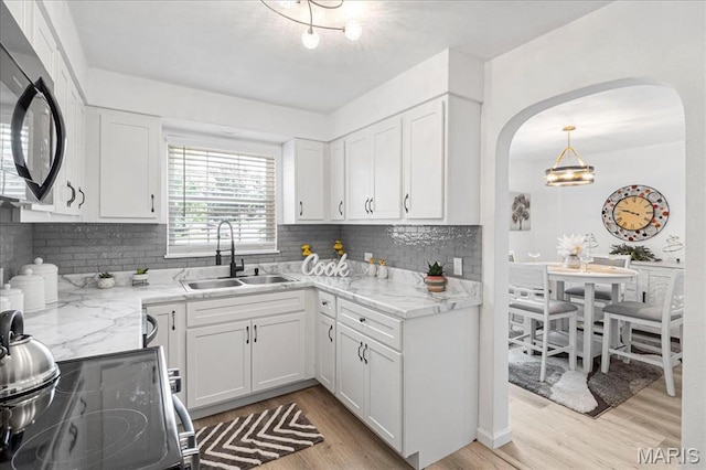 407 N 28th St, Belleville, IL 62226 - kitchen featuring arched walkways, light wood-style floors, decorative backsplash, and white cabinetry