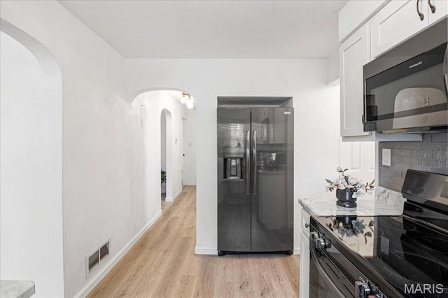 407 N 28th St, Belleville, IL 62226 - kitchen with appliances with stainless steel finishes, arched walkways, light wood-type flooring, and white cabinetry