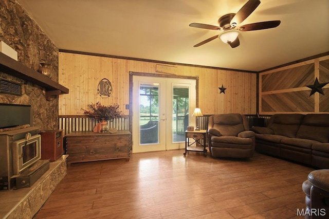 31337 Hudson Rd, Lebanon, MO 65536 - living area with french doors, a ceiling fan, wood walls, a wood stove, and hardwood / wood-style floors
