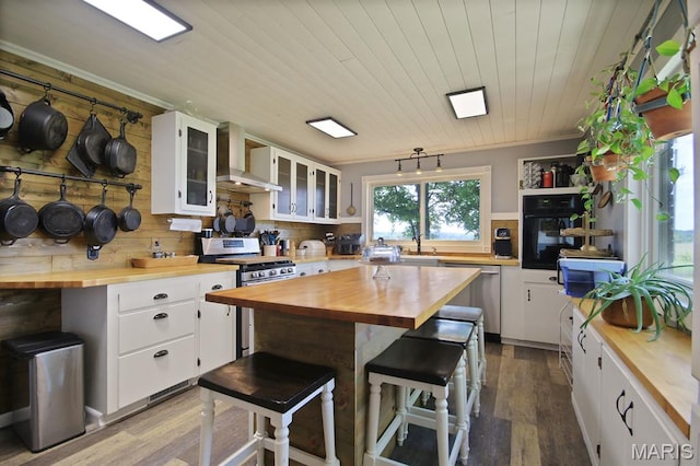31337 Hudson Rd, Lebanon, MO 65536 - kitchen with wood counters, wall chimney range hood, appliances with stainless steel finishes, dark wood-type flooring, and white cabinets