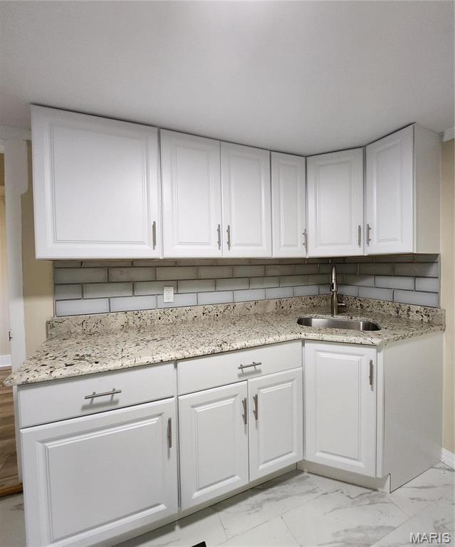 2020 S Brentwood Blvd, Saint Louis, MO 63144 - kitchen featuring light marble finish flooring, white cabinets, light stone counters, and backsplash