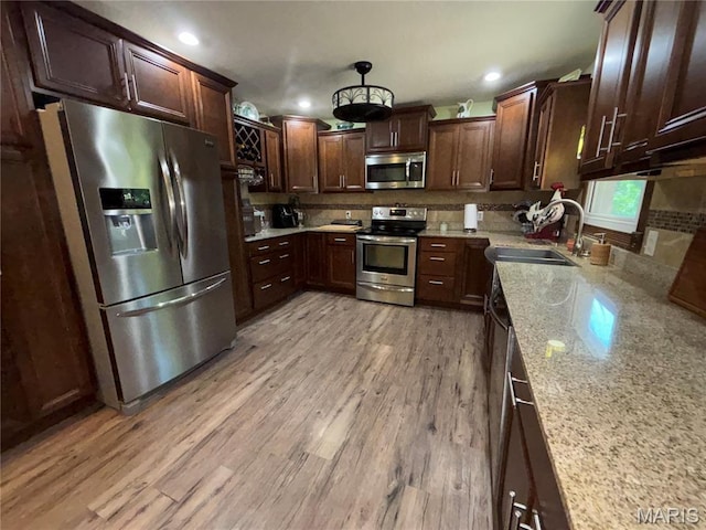 208 E Main St, Iberia, MO 65486 - kitchen featuring appliances with stainless steel finishes, recessed lighting, light stone counters, tasteful backsplash, and light wood-style floors