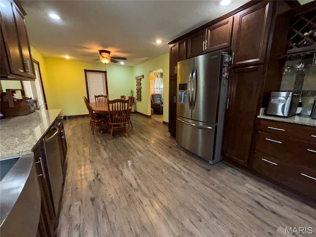 208 E Main St, Iberia, MO 65486 - kitchen featuring appliances with stainless steel finishes, ceiling fan, light wood-type flooring, arched walkways, and light stone counters