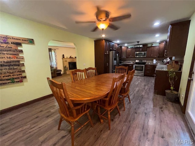 208 E Main St, Iberia, MO 65486 - dining room featuring arched walkways, dark wood-style floors, a ceiling fan, recessed lighting, and a fireplace with raised hearth