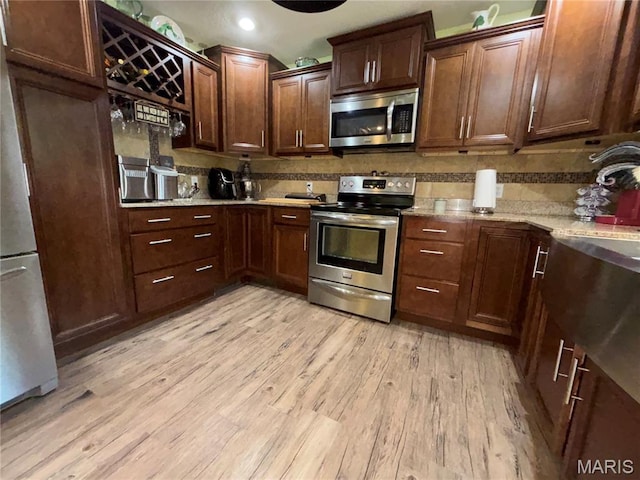 208 E Main St, Iberia, MO 65486 - kitchen with appliances with stainless steel finishes, backsplash, light wood-type flooring, light stone counters, and recessed lighting