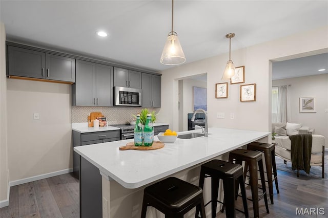 618 Maple Frst, Saint Louis, MO 63122 - kitchen with stainless steel appliances, a breakfast bar, backsplash, dark wood finished floors, and gray cabinets