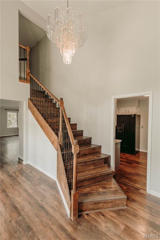 20055 Simmons Rd, Waynesville, MO 65583 - stairs featuring a towering ceiling, a chandelier, and wood finished floors