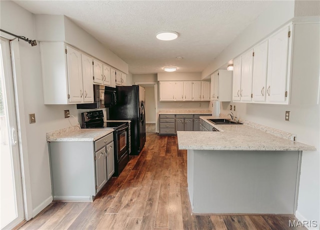 20055 Simmons Rd, Waynesville, MO 65583 - kitchen with black appliances, white cabinetry, a peninsula, wood finished floors, and a textured ceiling