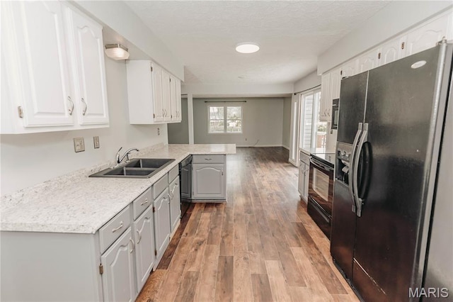 20055 Simmons Rd, Waynesville, MO 65583 - kitchen featuring black appliances, light wood finished floors, white cabinets, light countertops, and a textured ceiling