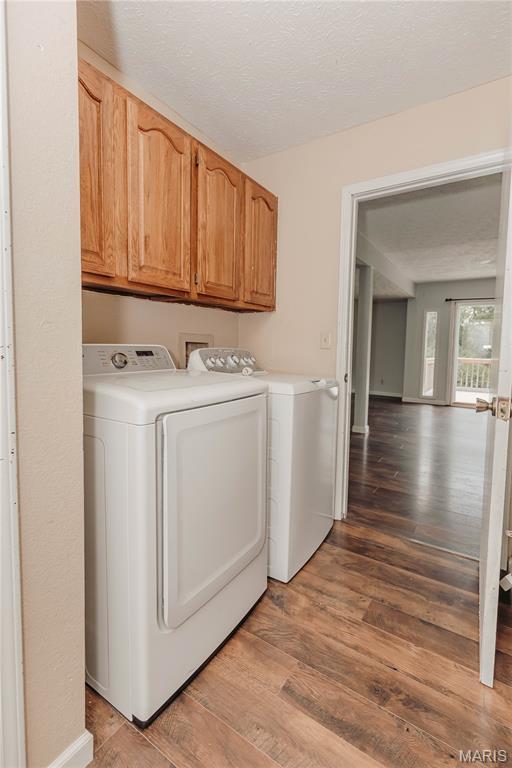 20055 Simmons Rd, Waynesville, MO 65583 - laundry area with washer and dryer, wood finished floors, and cabinet space