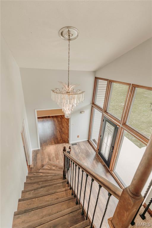 20055 Simmons Rd, Waynesville, MO 65583 - stairs with hardwood / wood-style flooring, a chandelier, and lofted ceiling