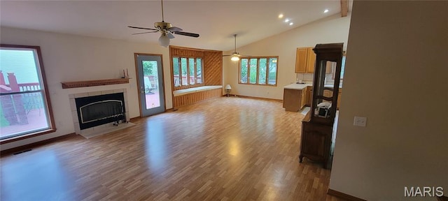 11112 Morrow Dr, Saint Ann, MO 63074 - unfurnished living room featuring light wood finished floors, a tiled fireplace, ceiling fan, recessed lighting, and high vaulted ceiling