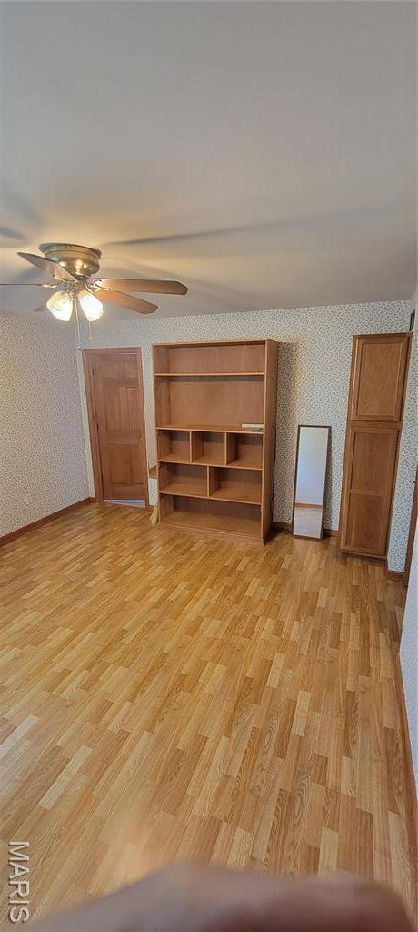 11112 Morrow Dr, Saint Ann, MO 63074 - unfurnished living room featuring wallpapered walls, light wood-type flooring, and ceiling fan