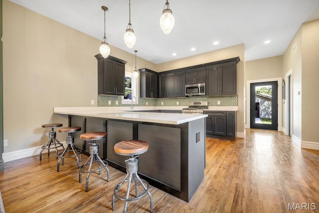 909 S 4th St, Saint Charles, MO 63301 - kitchen with stainless steel appliances, a breakfast bar area, decorative backsplash, a peninsula, and recessed lighting