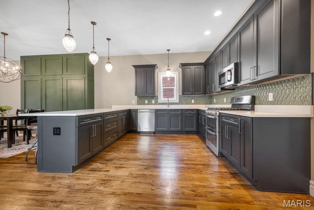 909 S 4th St, Saint Charles, MO 63301 - kitchen with stainless steel appliances, a peninsula, light countertops, tasteful backsplash, and hanging light fixtures