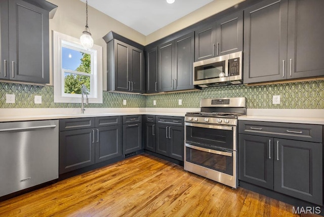 909 S 4th St, Saint Charles, MO 63301 - kitchen with stainless steel appliances, light countertops, light wood-style flooring, and hanging light fixtures