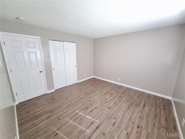 2465 Stoney End Ct, Florissant, MO 63031 - unfurnished bedroom with wood finished floors, a closet, and a textured ceiling
