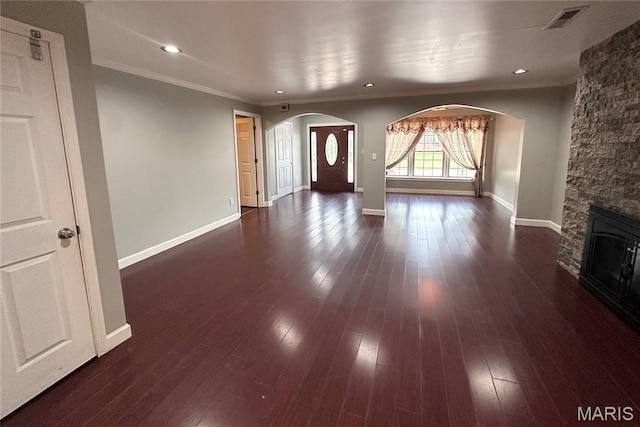 203 N Kingshighway St, Sikeston, MO 63801 - unfurnished living room with arched walkways, crown molding, dark wood-type flooring, a stone fireplace, and recessed lighting