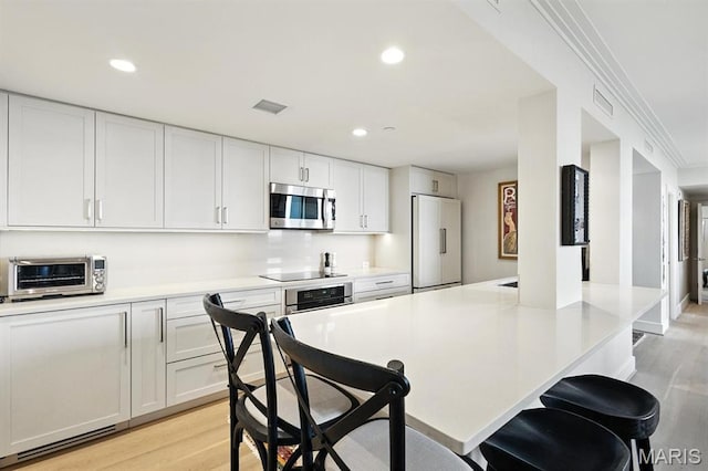 200 S Brentwood Blvd Unit 15C, Clayton, MO 63105 - kitchen featuring stainless steel appliances, a breakfast bar, light wood finished floors, and recessed lighting