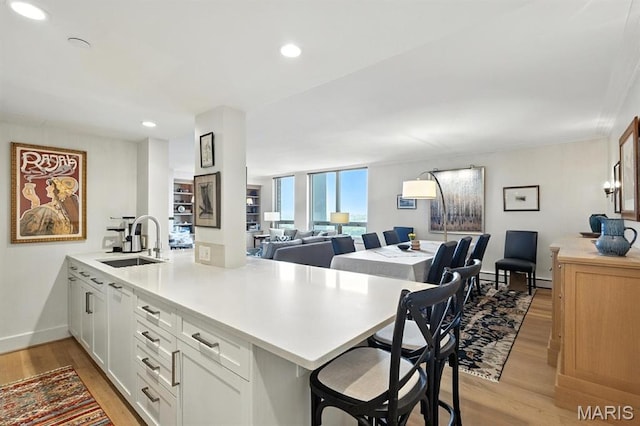 200 S Brentwood Blvd Unit 15C, Clayton, MO 63105 - kitchen featuring a peninsula, light wood-type flooring, a breakfast bar area, light countertops, and open floor plan