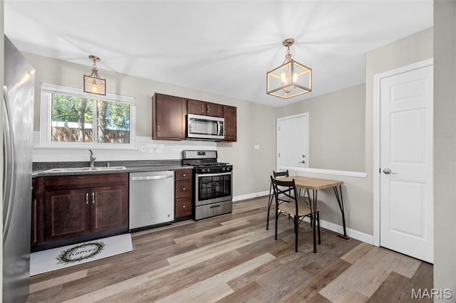 4035 Mary Ridge Ln, Saint Charles, MO 63304 - kitchen featuring stainless steel appliances, dark countertops, a chandelier, dark brown cabinets, and light wood-style floors