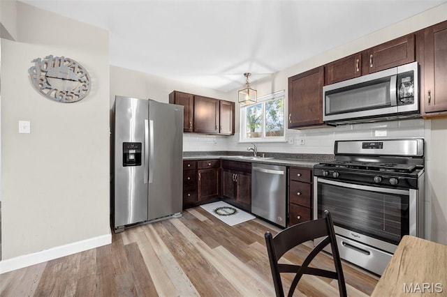 4035 Mary Ridge Ln, Saint Charles, MO 63304 - kitchen featuring stainless steel appliances, dark brown cabinets, light wood-style floors, dark countertops, and tasteful backsplash